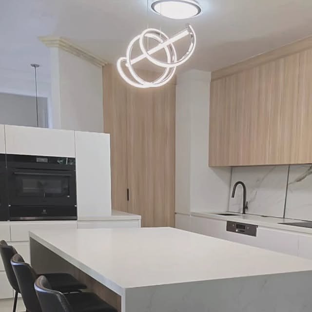Two-tone oak and white kitchen with waterfall stone island and designer pendant