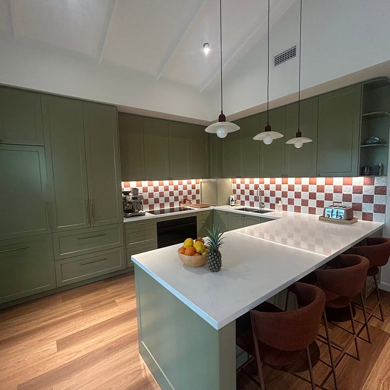Sage green kitchen with checkered splashback and pendant lights