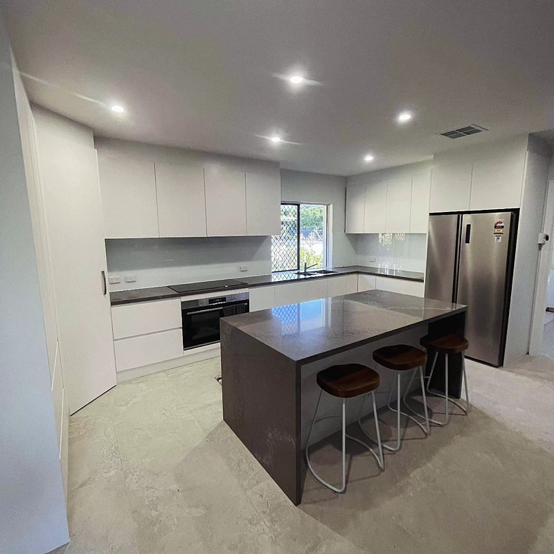 White kitchen with dark island bench and stools