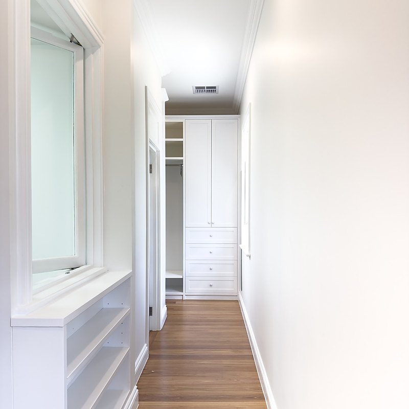 Walk-in robe with built-in white cabinetry, drawers and shelving