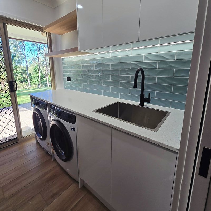 Laundry with teal subway tile splashback