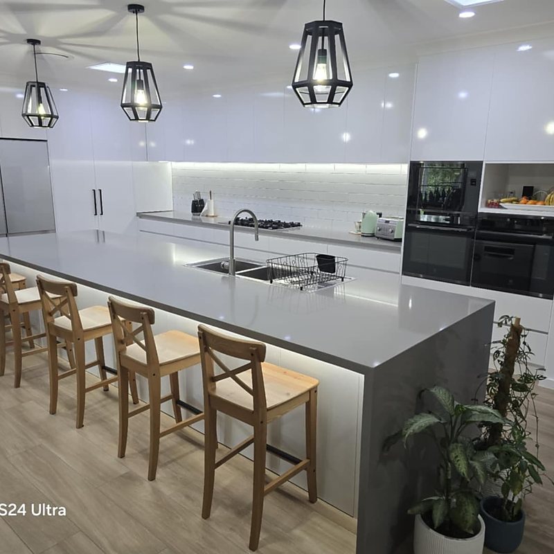 White kitchen with black cage pendants and long island